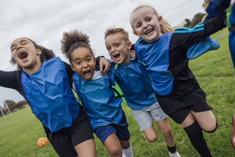 Front view of a small group of boys and girls wearing sports clothing, football boots and a sports bib on a football pitch in the North East of England. They are at football training where they are doing different football training drills. They are running and celebrating with their arms around each other while smiling and looking at the camera.
Videos are available for this scenario.